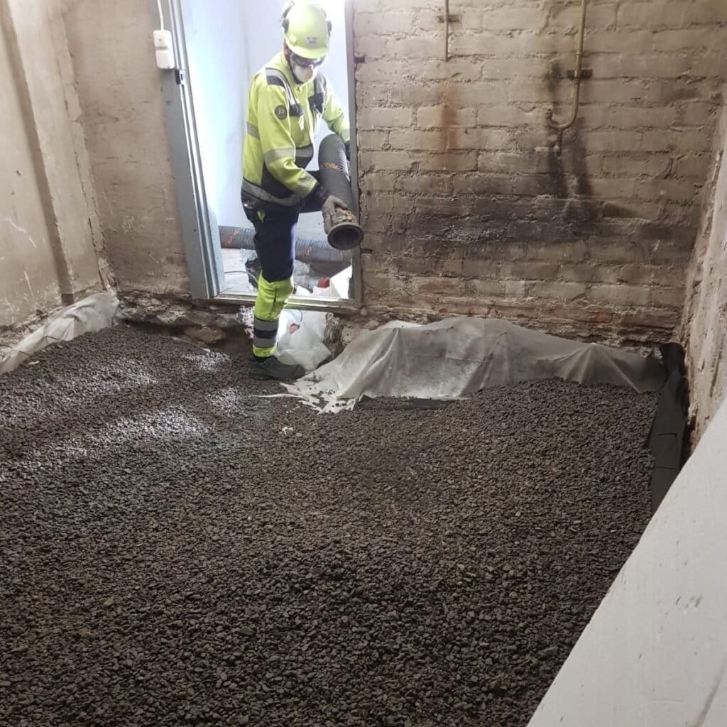 Ekoeristeen asentaja puhaltaa sepeliä alapohjaan